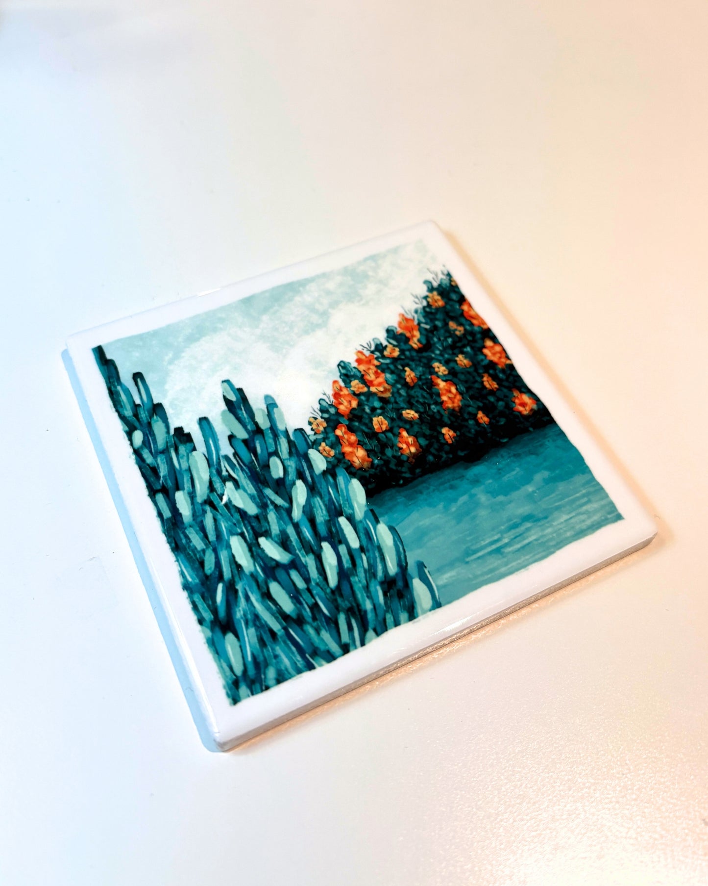 Coaster with a pine tree and lake art design on a light background