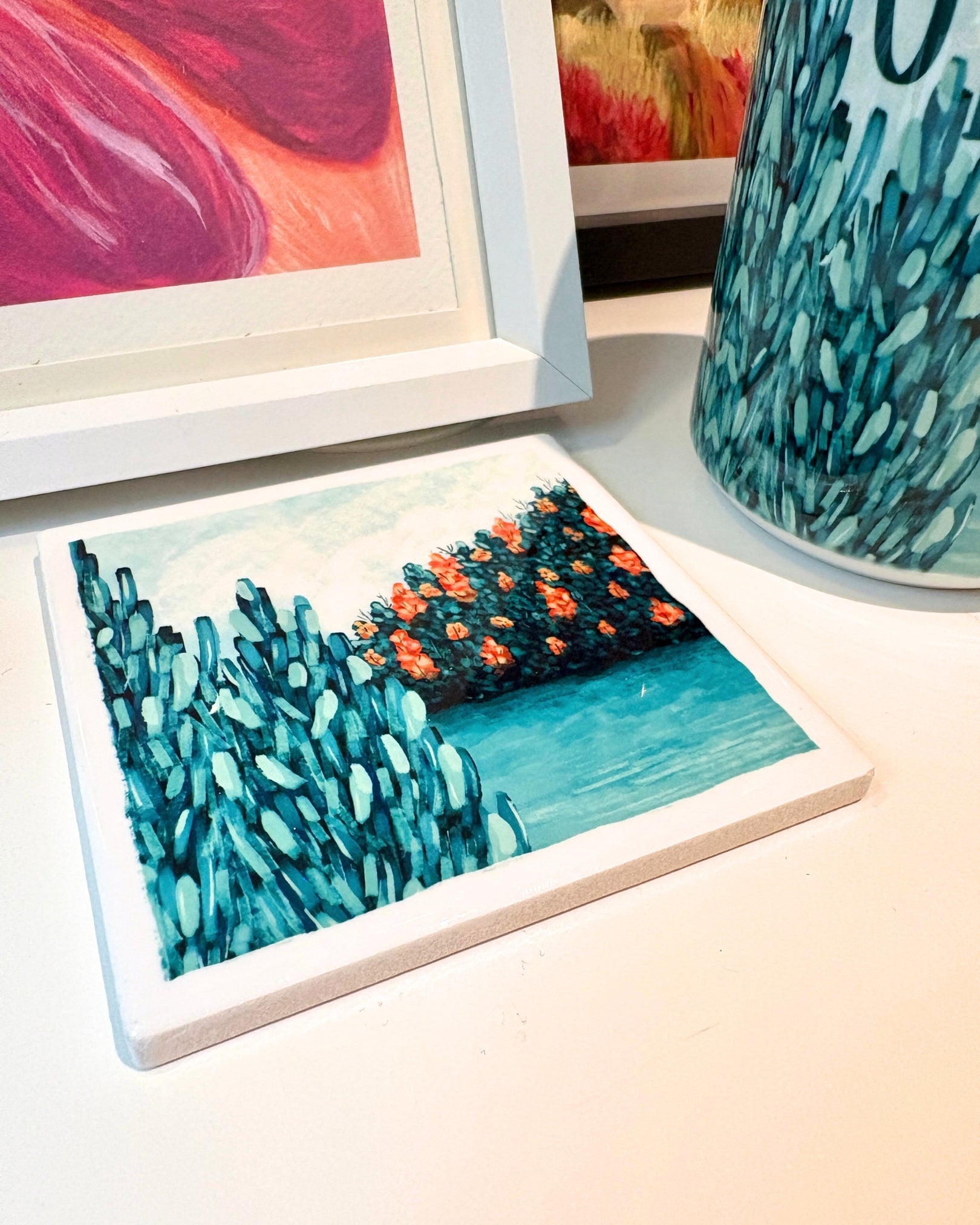 Coaster with pine tree and lake design on a table next to other decorative items