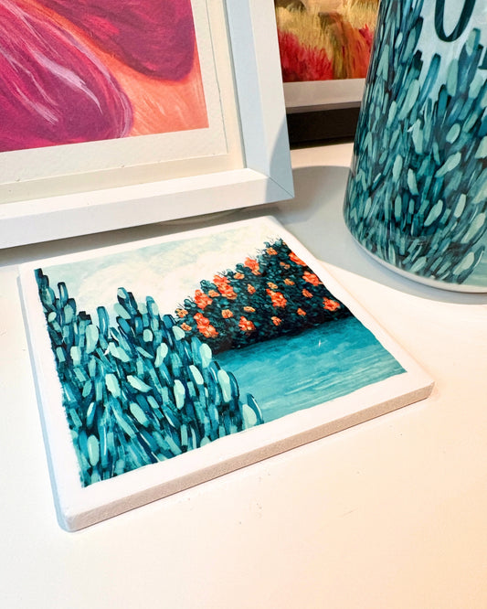 Coaster with pine tree and lake design on a table next to other decorative items